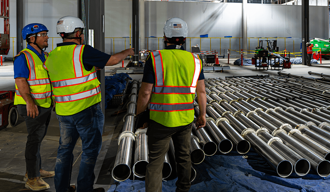 Workers in a plant with transport ducting installed to remove industrial dust and other contaminants.