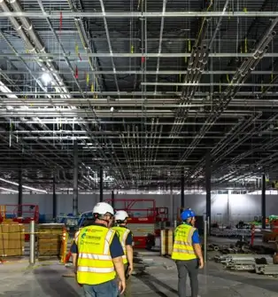 Industrial workers in a facility with overhead transport ductwork for dust and fume extraction.